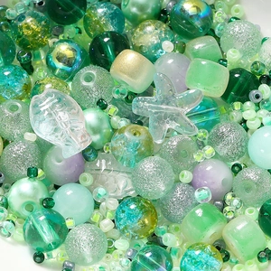 Macro view of green themed DIY jewelry bead mix with pearls and glass starfish charms