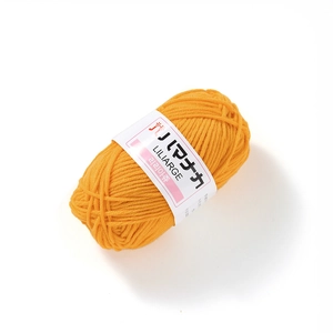 Close-up of soft orange milk cotton yarn ball showing 4-ply twisted texture and paper band
