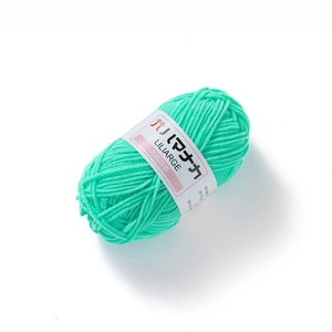 Close-up of mint green 4-ply milk cotton yarn ball with white paper label for DIY crafts