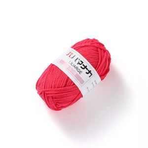 Detailed view of rose pink 4-ply milk cotton yarn roll with white paper label on white background
