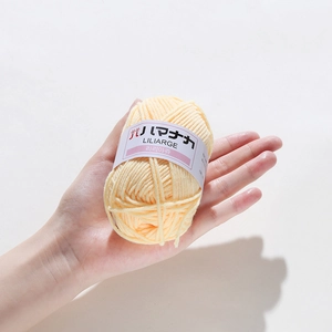 Liliarge soft yellow 4-ply milk cotton yarn ball held by hand for crochet and knitting