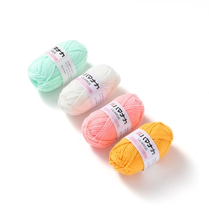 Close-up of four-strand milk cotton yarn rolls in pastel mint, white, pink, and yellow