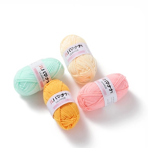 Detailed macro of 4-ply cotton milk yarn rolls in soft pastel colors for DIY crochet