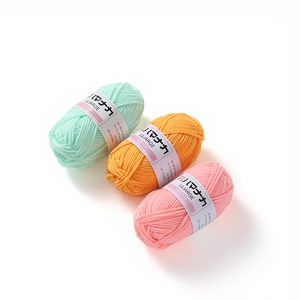 Detail of mint green, orange and pink 4-ply milk cotton yarn rolls for crochet and knitting