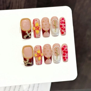 Faux ongles faits main avec fleurs 3D, perles et reliefs de roses dorées sur tons roses