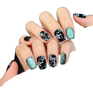 Black and blue press-on nails with blue floral patterns and glitter cat-eye finish