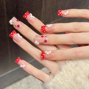 Handmade press-on nails with red polka dot French tips and 3D floral ladybug accents