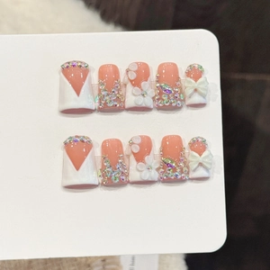 Pink and white handmade press-on nails with 3D floral bows and colorful rhinestones