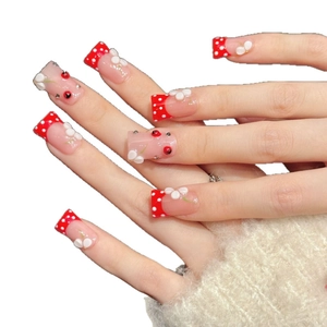 Red press-on nails with white polka dots, 3D floral accents, and square tip shape