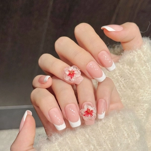 Pink and white French press-on nails with 3D floral embellishments on long oval tips