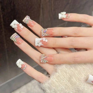 Pink and white handmade press-on nails with 3D bows and colorful rhinestone accents