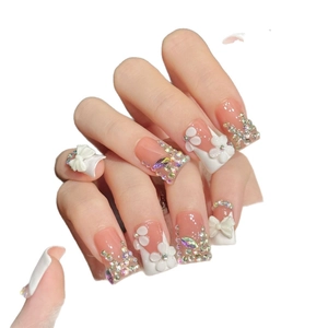 Handmade pink and white press-on nails with 3D floral accents and sparkling rhinestones