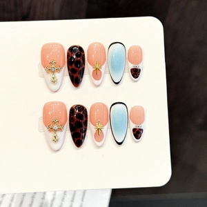 Pink leopard print press-on nails with golden star and cross metal accessories