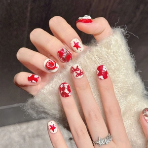 Faux ongles faits main avec étoiles rouges et nœuds 3D sur des capsules courtes rondes