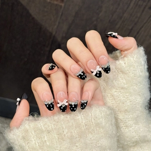 Polka dot press-on nails with pink bows and rhinestones on almond shaped almond tip