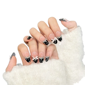 Almond-shaped press-on nails with black polka dots, pink 3D bows, and rhinestone accents