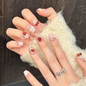 Pink press-on nails with 3D strawberry, flower and pearl charms on model hands