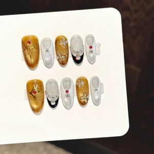 Faux ongles faits main œil-de-chat ambre avec strass rouges et motifs d'étoiles