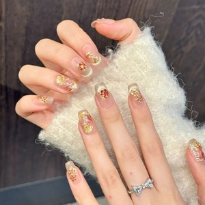 Faux ongles faits main avec feuilles d'or, motifs floraux ambrés et reflets œil de chat