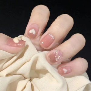 Faux ongles faits main rose nude avec cœurs 3D blancs, perles et nœuds roses
