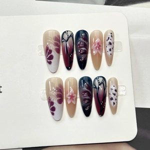 Vue détaillée des faux ongles amande avec motifs floraux bordeaux et textures papillon