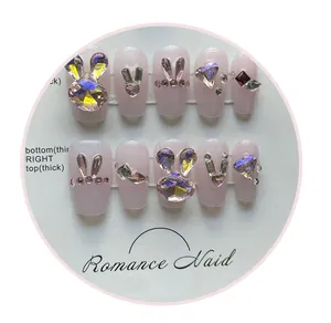 Close-up of 3D crystal rabbit and heart charms on translucent pink press-on nails