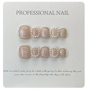 Macro detail of handmade nude floral press-on toenails with pearl and gold chain trim