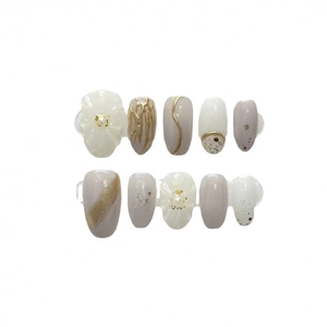 Elegant handmade press-on nails with 3D flower relief and gold accents on nude gray base
