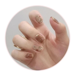 Macro detail of amber marble press-on nails with elegant gold foil trim accents
