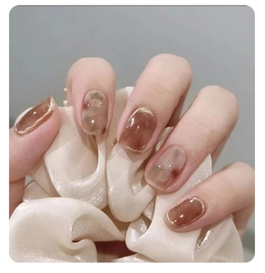 Detail of amber marble press-on nails with gold edges and elegant oval shape design
