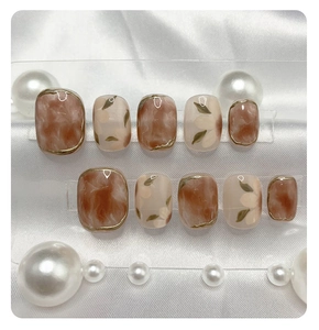 Detail of handmade press-on nails with marble smudge and floral patterns on white silk