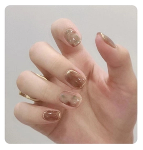 Short round nail tips with brown marble gradient and gold edge details on model hand