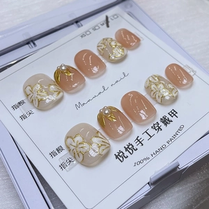 Détail de faux ongles faits main avec art floral, perles et carte de taille