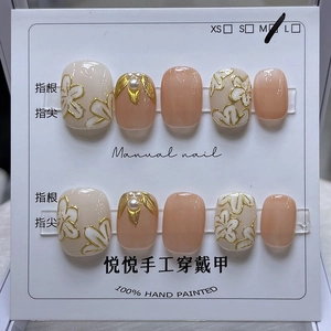 Détail de faux ongles faits main avec motifs floraux roses, bords dorés et perles