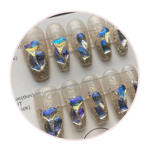 Macro shot of long coffin press-on nails with iridescent heart gems and gold glitter gradient