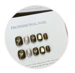 Detail of handmade olive green press-on nails with golden heart charms and crystals