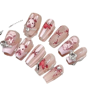 Pink press-on nails set with bunny patterns and 3D heart rhinestones on white background