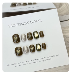Detailed view of handmade emerald green press-on nails with 3D hearts and rhinestones