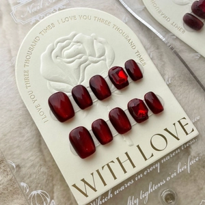 Deep burgundy cat eye press-on nails set with ruby gemstones on embossed card