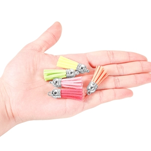 Mini suede tassels in five vibrant colors with silver metal caps shown in palm for size