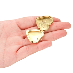 Macro view of golden heart-shaped locket with Mon Ami engraved detail on the inner side