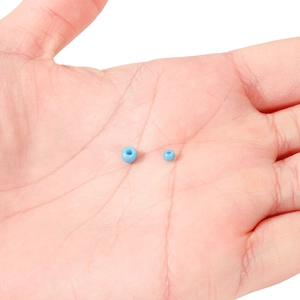 Nahaufnahme himmelblauer 4mm Glasperlen auf der Handfläche für DIY Schmuckherstellung