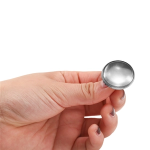 Polished stainless steel round bezel earring studs held by hand for scale reference