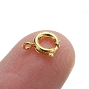 Macro shot of 6mm gold spring clasp for necklaces held on a fingertip for scale