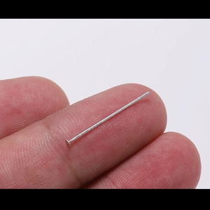 Chiodini a testa piatta in acciaio inox su un dito per mostrare la misura dell'accessorio