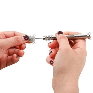 Macro detail of a silver hand drill tool piercing a glitter resin bear for DIY crafts