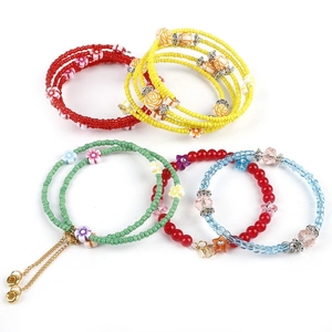 Detail of four colorful beaded bracelets with floral and star charms in a flat lay view
