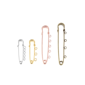 Macro shot of four sizes of metal safety pins with loops for DIY jewelry making