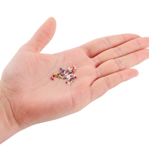 Macro shot of 2mm colorful glass seed beads held in hand for size comparison