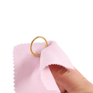 Polished gold minimalist ring being cleaned with a pink jewelry polishing cloth